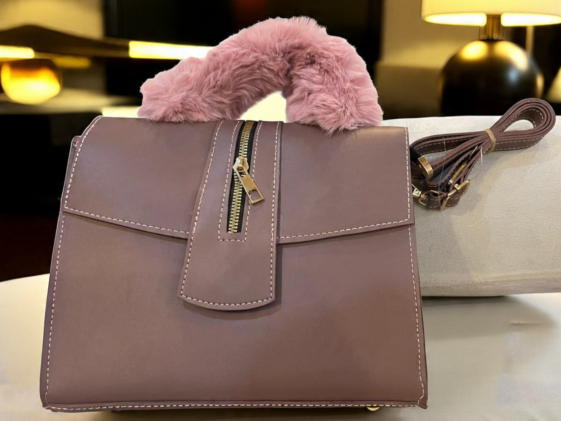 Grayish Purple handbag with a fluffy pink handle on a white surface.