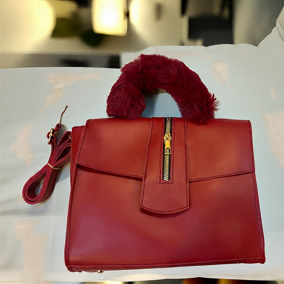 Red handbag with a fluffy pom-pom on a white surface