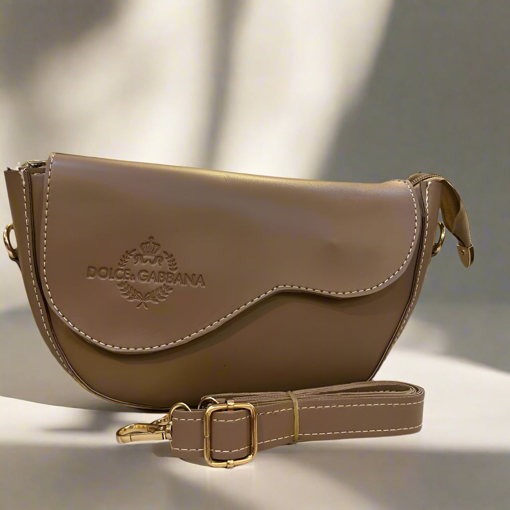 Medium Brown leather bag with gold accents on a marble surface, with a blurred background of furniture.